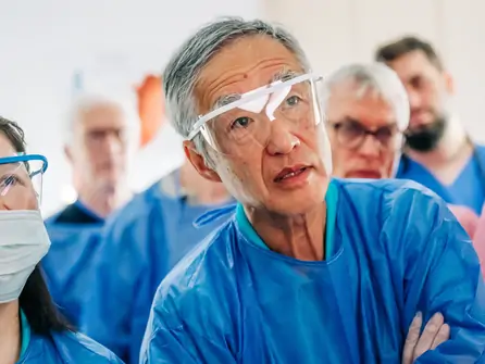 Ärzteteam in blauen Schutzkitteln und medizinischer Schutzbrille in einem Krankenhaus