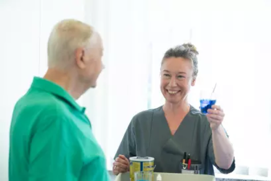 Zwei Personen im Gespräch, eine hält ein Glas mit blauem Getränk, die andere trägt grüne Kleidung