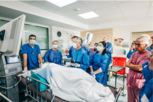 Ärzteteam in blauen OP-Kitteln führt eine medizinische Untersuchung an einem Patienten im Krankenhaus durch