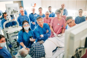 Ärzteteam in blauer und rosa Schutzkleidung führt eine medizinische Untersuchung an einem Patienten im Krankenhaus durch