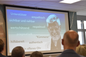 Präsentation mit Stichwörtern wie 'Unterstützer', 'empathisch', 'sichtbar und nahbar', 'wertschätzend', 'respektvoll', 'pragmatisch', 'hilfsbereit', 'authentisch' und 'ein offenes Ohr' vor Publikum