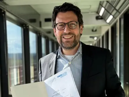 Mann in Anzug hält Dokument in einem modernen Büroflur