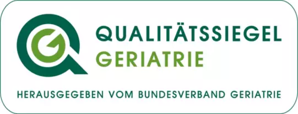 Rechteckiges Logo mit stilisiertem grünen Lupensymbol und Text 'QUALITÄTSSIEGEL GERIATRIE HERAUSGEGEBEN VOM BUNDESVERBAND GERIATRIE'